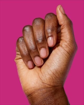 Eine Hand mit kurzen Fingernägeln vor einem pinken Hintergrund.