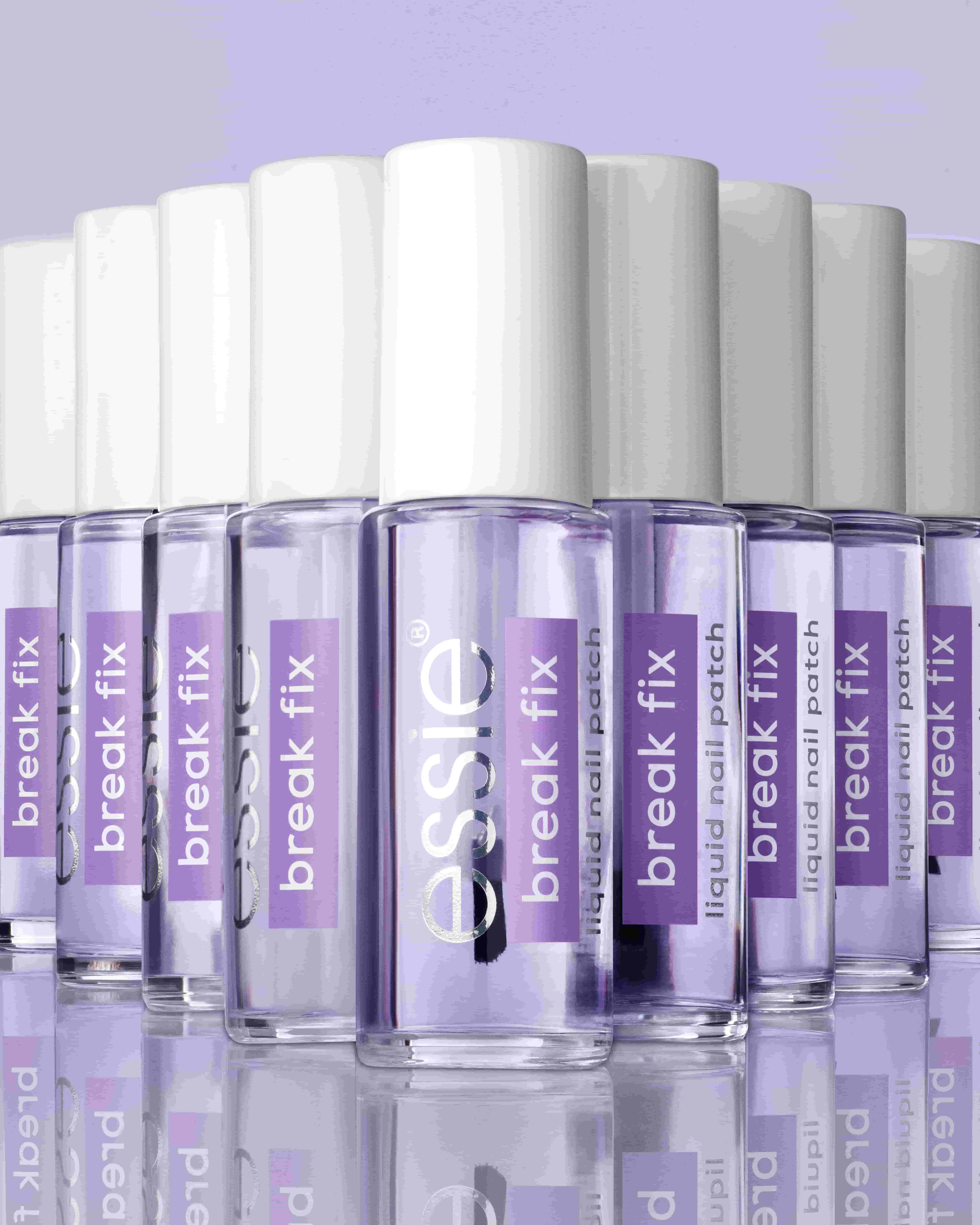 Mehrere Flschen essie Break Fix auf spiegelndem Untergrund und vor lila Hintergrund