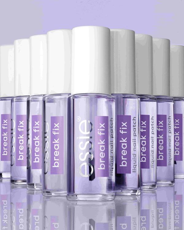 Mehrere Flschen essie Break Fix auf spiegelndem Untergrund und vor lila Hintergrund