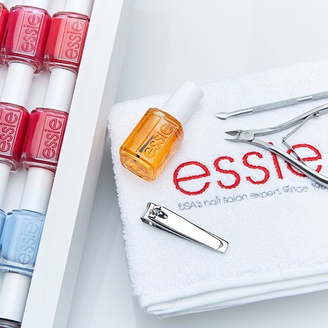 essie Nagelöl auf einem Handtuch mit essie Schriftzug und Nagelscheren.