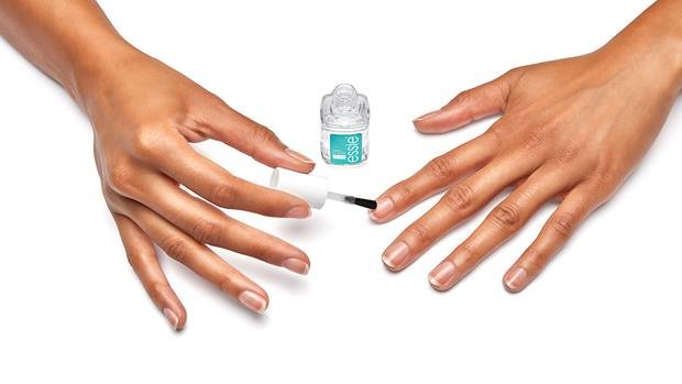 Die Hände von jemandem, der einen essie base coat auf seine Nägel aufträgt