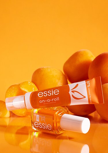essie Nagelhautöl im klassischen Flaschenformat und im on a roll-Format mit Aprikosen im Hintergrund