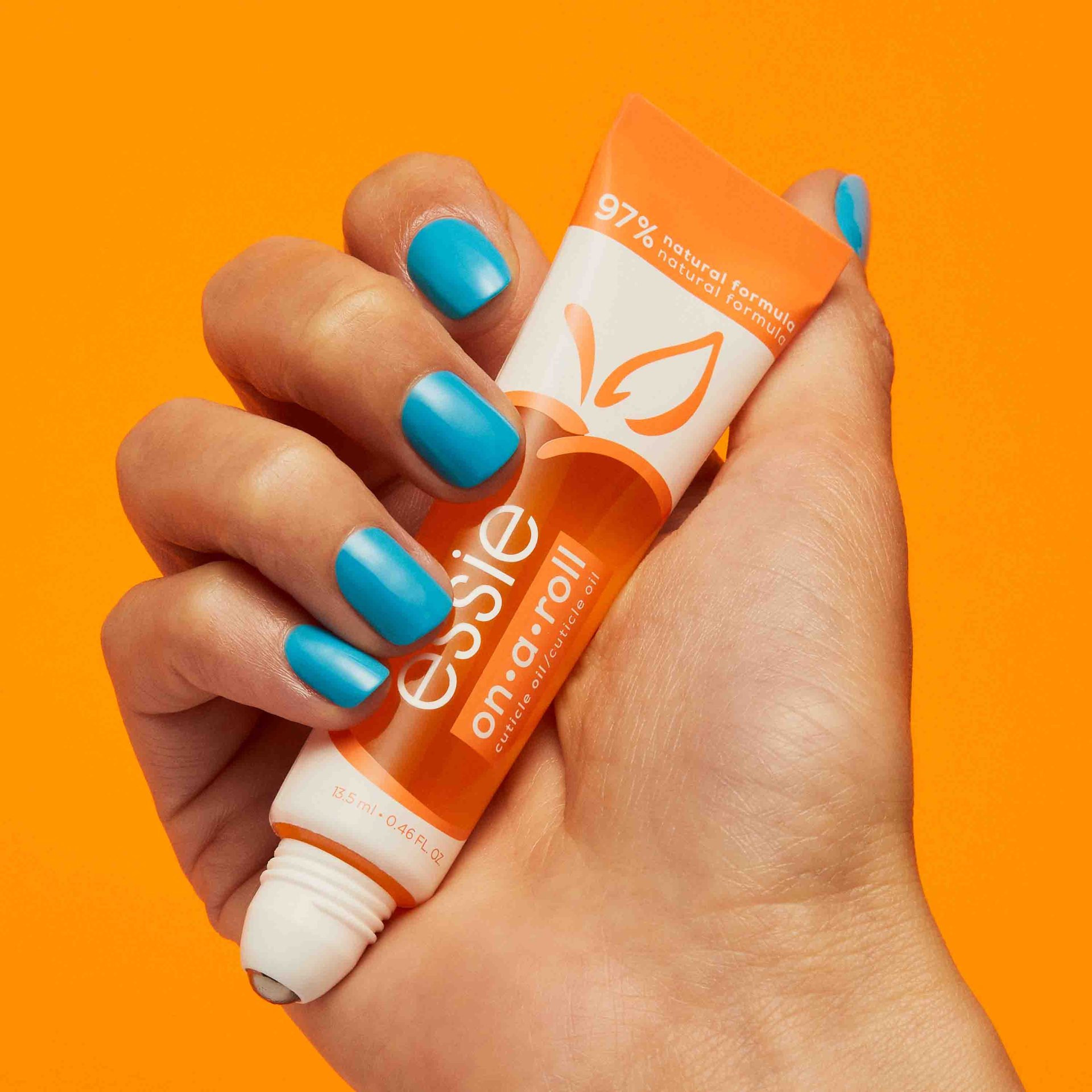 Hand mit blauer Maniküre die essie on a roll apricot nail & cuticle oil hält